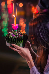 Midsection of woman holding illuminated flower