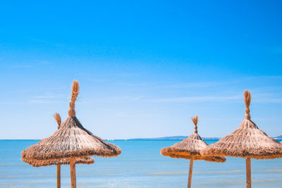 Traditional windmill on beach against blue sky