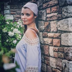 Portrait of woman standing against brick wall