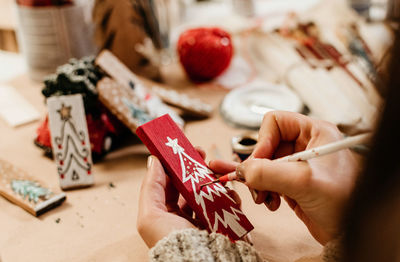 Selective focus, close-up of hand holding paintbrush, crafting christmas ornaments.