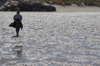 Full length rear view of man walking on beach