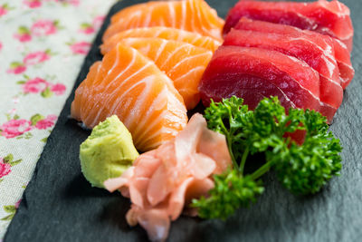 Close-up of sashimi on slate at table against black background