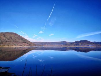 Scenic view of lake and mountains against blue sky