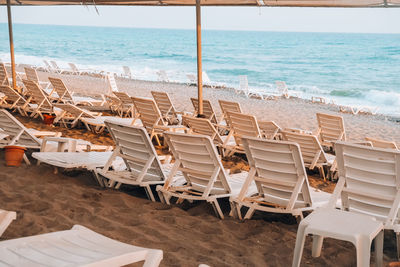 Chairs on beach by sea against sky