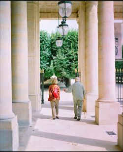 Rear view of people walking on colonnade