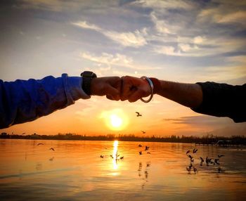 People enjoying in lake against sky during sunset