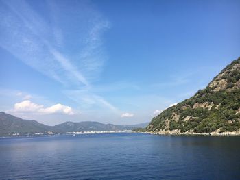 Scenic view of sea and mountains against blue sky