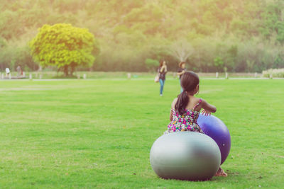 Rear view of woman sitting on grassy field