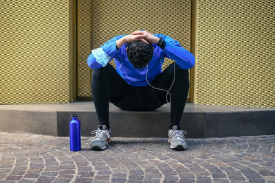 Male doing stretching and listening music after workout. man resting during city jogging. runner 