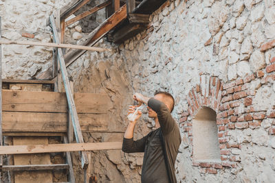 Full length of man photographing against wall