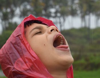 Close-up portrait of boy trying to drink rain water