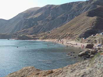 Scenic view of sea and mountains and people at the beach 