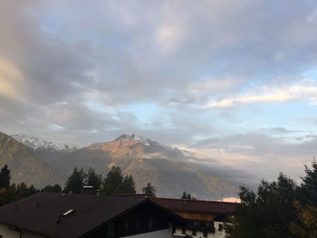 Panoramic view of buildings and mountains against sky at sunset