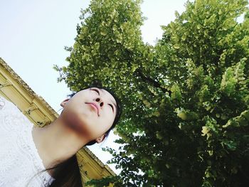 Low angle view of young woman against trees