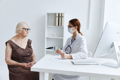 Woman using phone while sitting on table