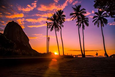 Silhouette palm trees on beach against romantic sky at sunset