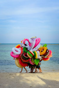 Low section of people with colorful inflatable rings for sale at beach