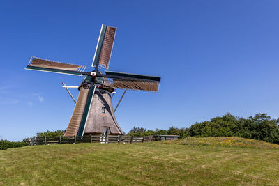 Low angle view of windmill against clear blue sky