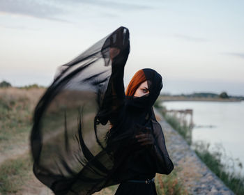 Full length portrait of woman standing against sky