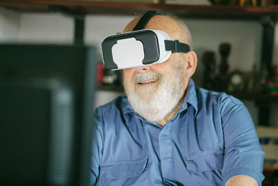 Senior man using virtual reality simulator and computer