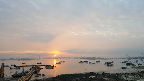 Boats moored at harbor against sky during sunset