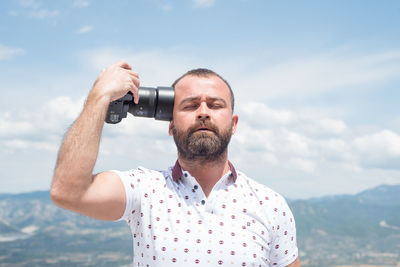 Man holding camera against sky