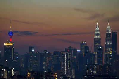 Illuminated buildings in city at sunset