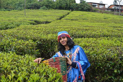 Portrait of young woman wearing traditional clothing standing amidst tea plants