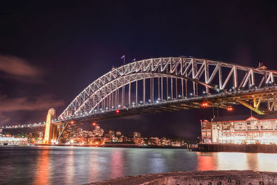 Illuminated bridge over river at night