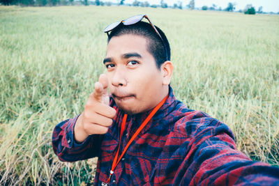 Portrait of young man standing on grassy field