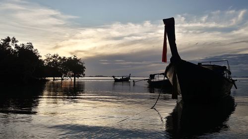 Silhouette boats moored on sea against sky during sunset