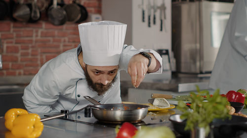 Chef sprinkling salt on food in kitchen