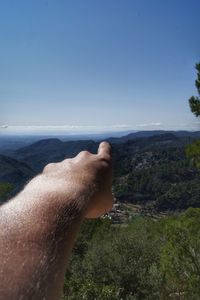 Close-up of hand on mountain against sky