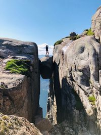 Man standing amidst rock formation against sky