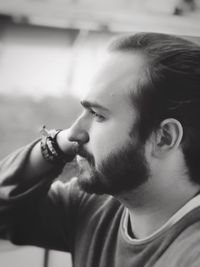 Close-up side view of young bearded man looking away