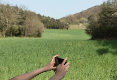 Midsection of person holding umbrella on field