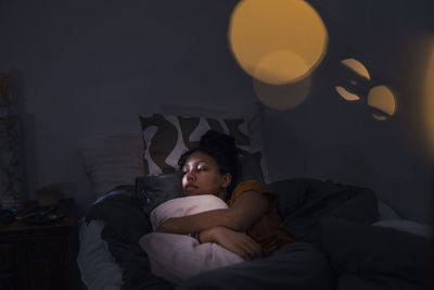 Pensive young woman lying in bed