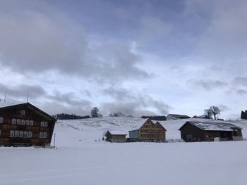 Houses on snow covered landscape against sky