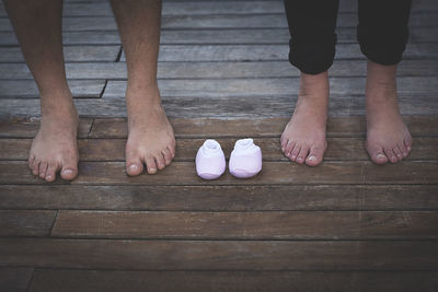 Low section of man and woman standing by baby shoes