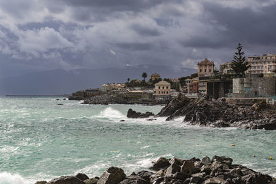 Sea by buildings against sky