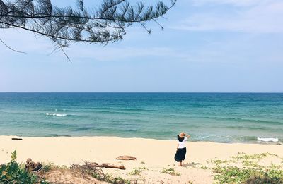 Woman standing on beach against sky