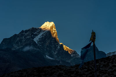 Low angle view of snowcapped mountain against blue sky