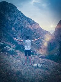 Rear view of man standing on mountain against sky