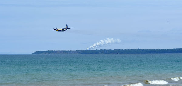 Airplane flying over sea against blue sky