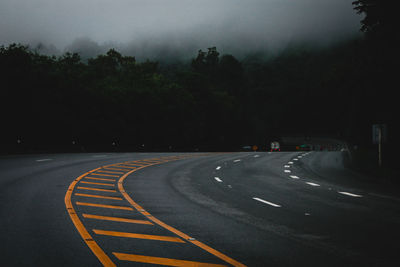 Road by trees against sky at night