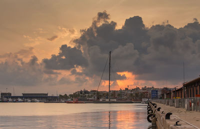 Sailboats moored at harbor against sky during sunset