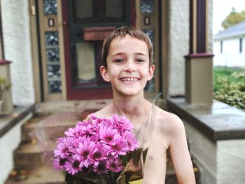 Portrait of smiling shirtless boy holding bouquet