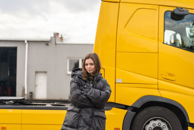 Side view of young woman standing in car