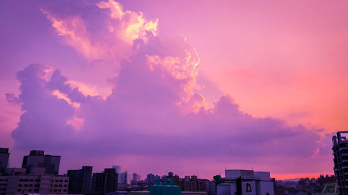 Buildings in city against dramatic sky