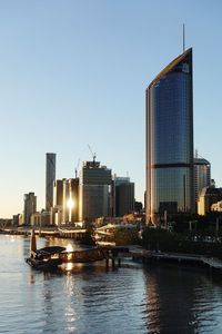 River by modern buildings against clear sky